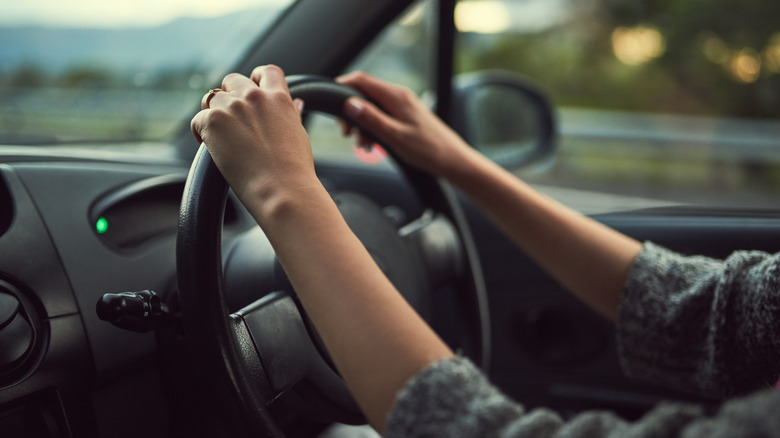 A woman driver with her hands positioned at 10 o'clock position on the steering