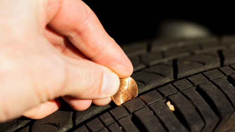 A person using a U.S. penny to check the level of tread remaining on their tire.