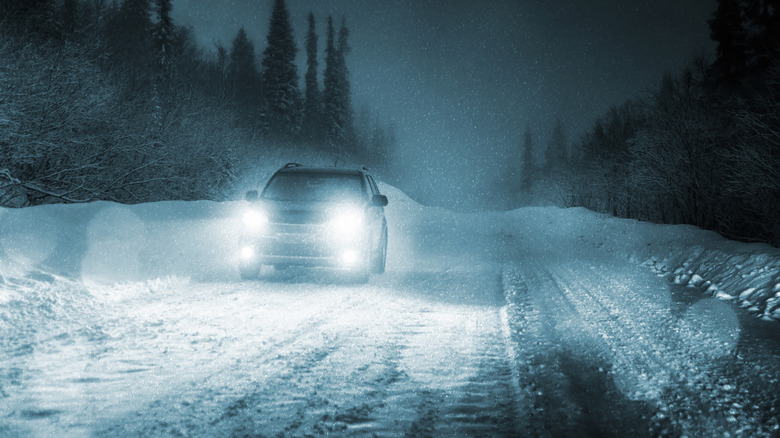 A car with full beams driving through a winter night