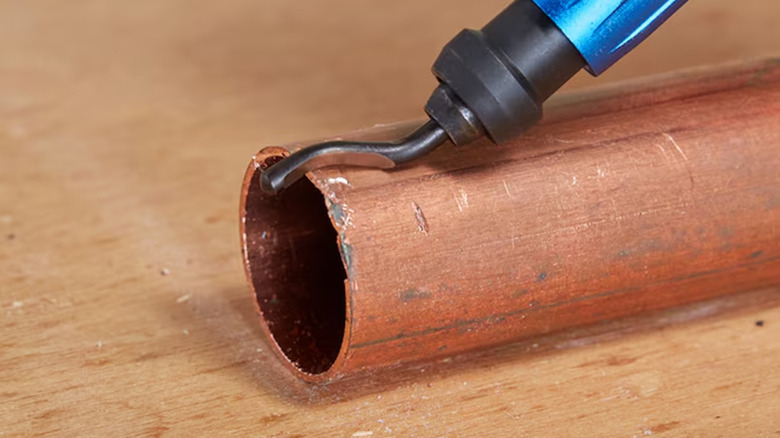 A deburring tool smoothing out the edges of a pipe
