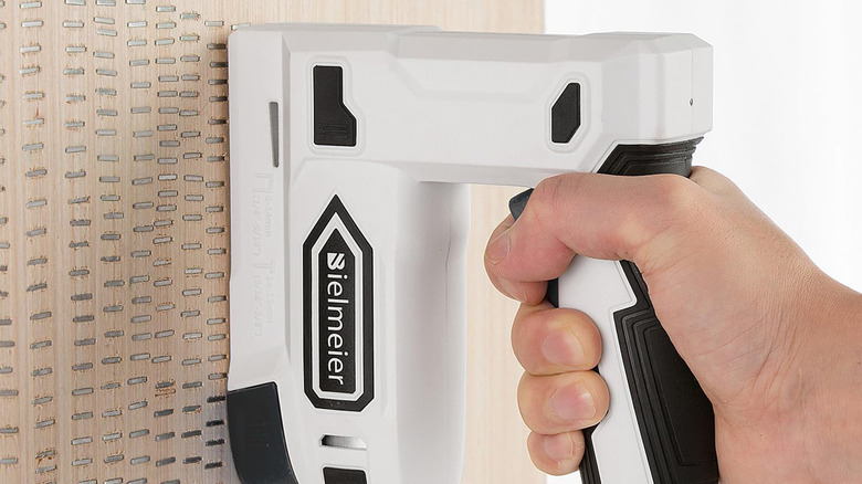 A man putting many nails into a piece of wood