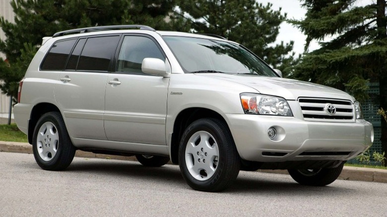 Silver 2007 Toyota Highlander parked on a road with trees in the background.
