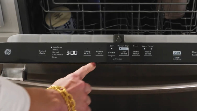Woman pushing the bottle jets button on a GE dishwasher