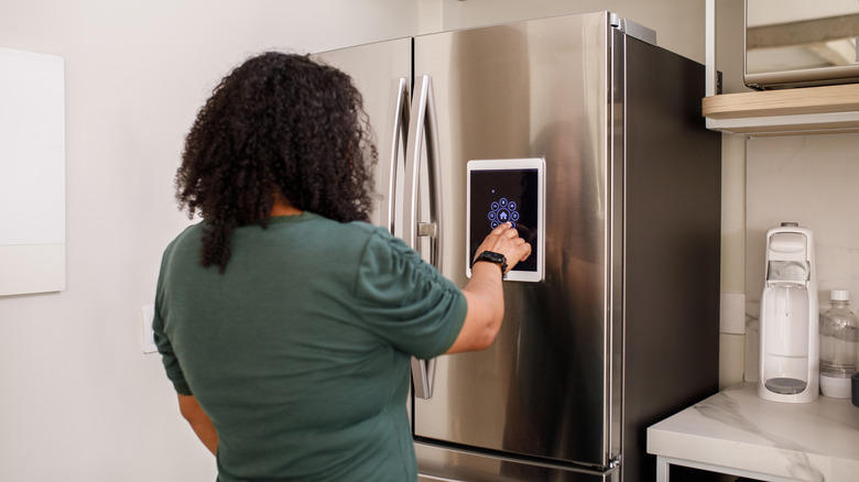 Woman using smart refrigerator menu