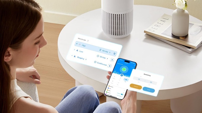 A woman looking at her phone in front of an air purifier.