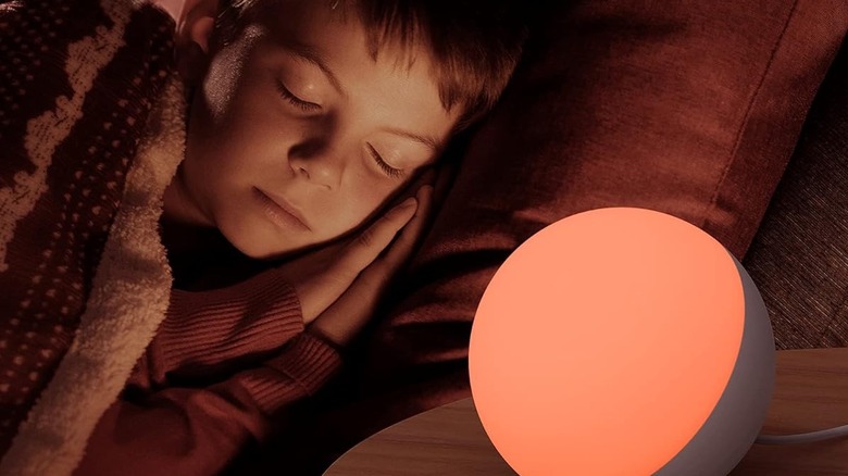 A child sleeping next to a smart table lamp.