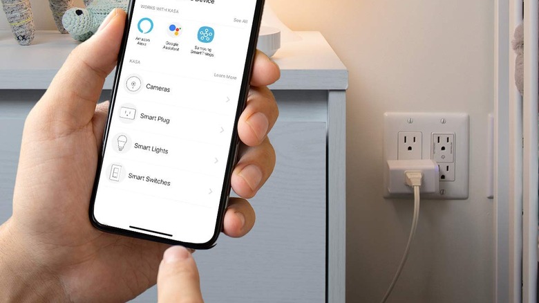 A person about to press a menu button with a smart plug in the background.