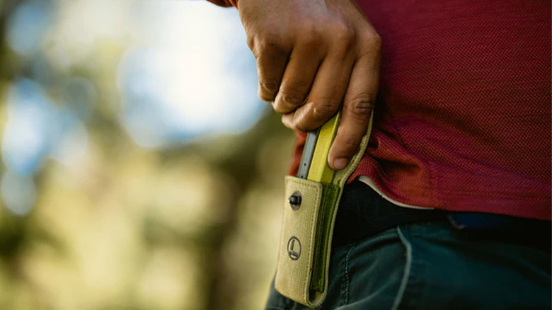 A person holstering a Leatherman multitool
