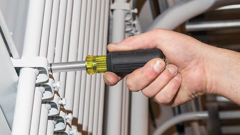 A man using a Klein screwdriver on a metal bracket