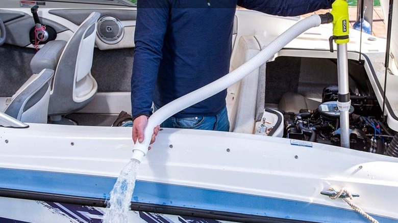 A person using a Ryobi pole pump to drain a boat's engine bay.