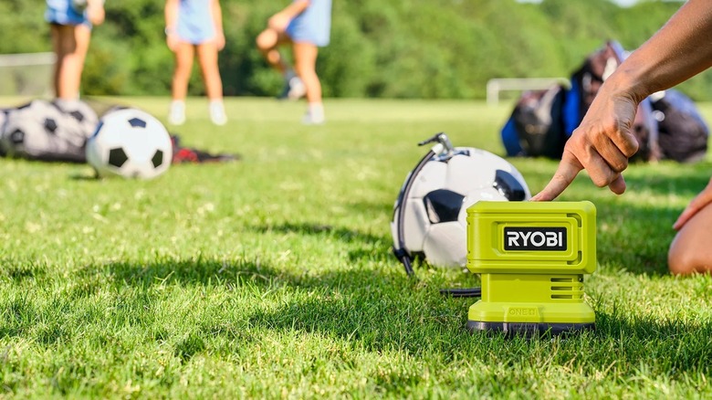 A person using a Ryobi inflator to blow up a soccer ball