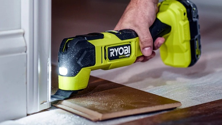 A person cutting wall trim with a Ryobi multi-tool