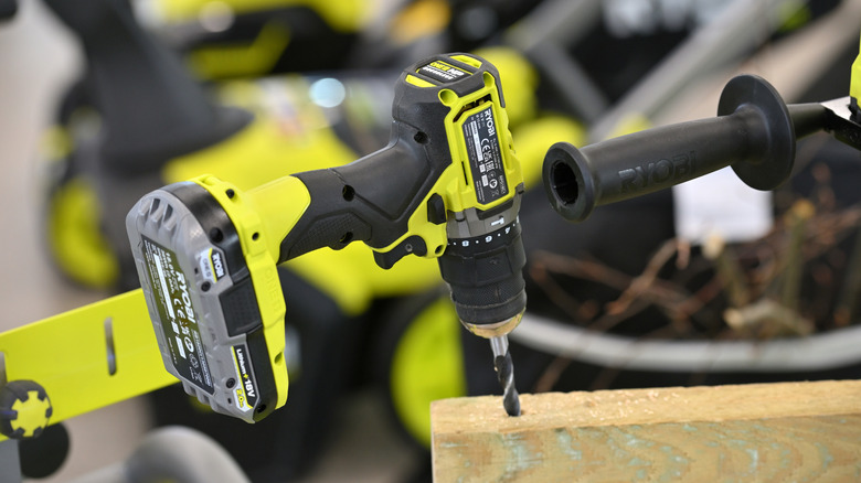 A cordless Ryobi power drill drilling into wood