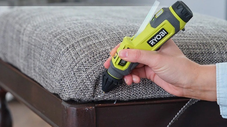 Person using a Ryobi glue pen to fix chair upholstery
