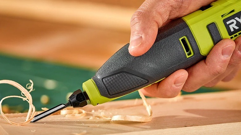 A person using a Ryobi power carver on a piece of wood