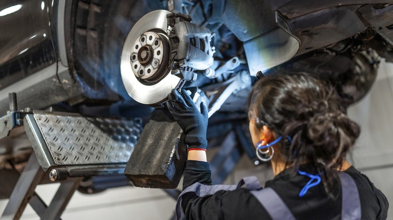A mechanic working on the brake system of a raised car.