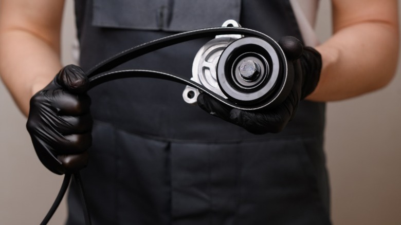 A mechanic holding a serpentine belt