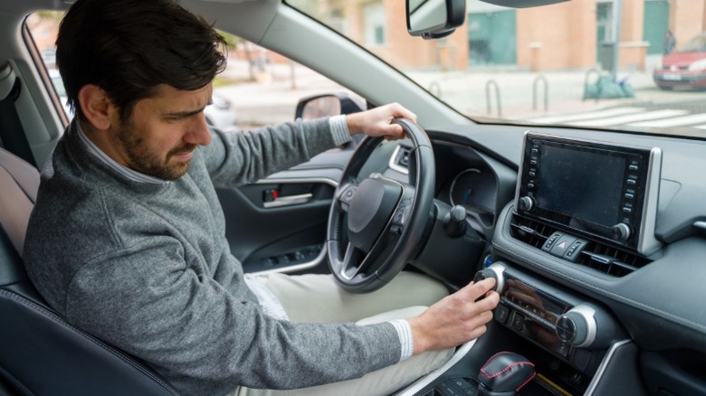 A man adjusting his car radio volume