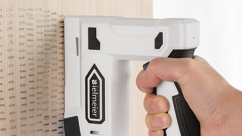 A staple gun being used on a piece of wood