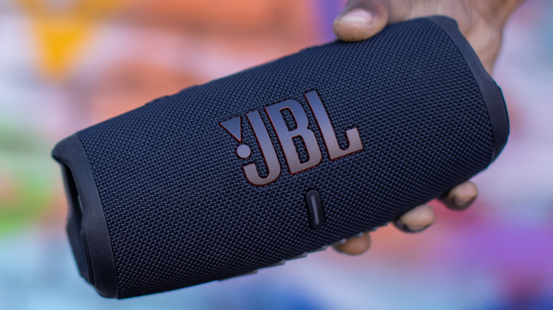 A person holding a JBL Charge 5 Bluetooth speaker