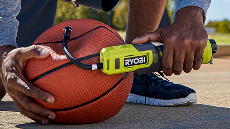 A man pumping up a basketball with a Ryobi infaltor