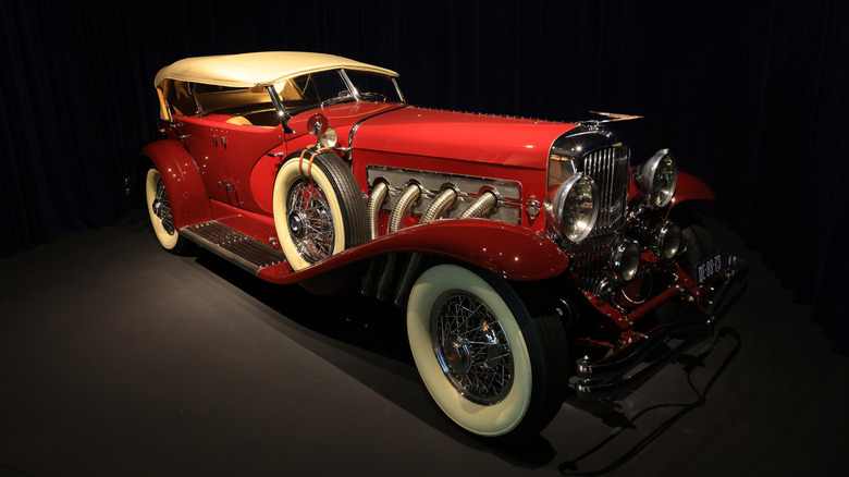 A red Duesenberg Model J from 1929 finished here in the Torpedo body style, showing off side exhaust pipes.