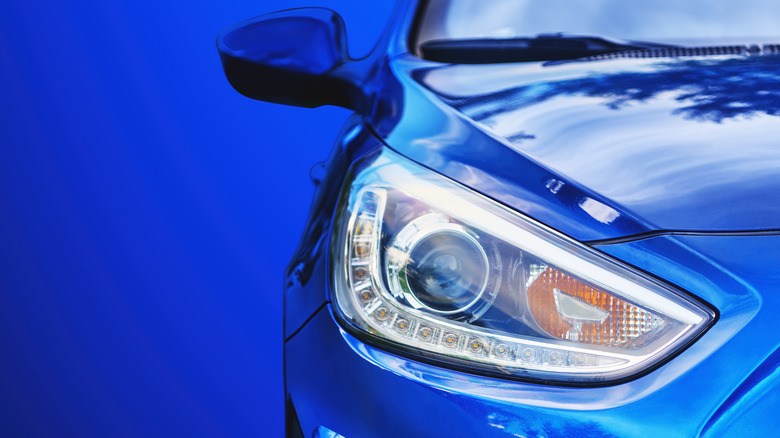 Closeup of a vehicle headlight on a blue car