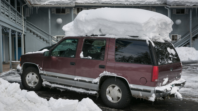 Parked Chevy Tahoe with clear windows and several feet of snow on the roof