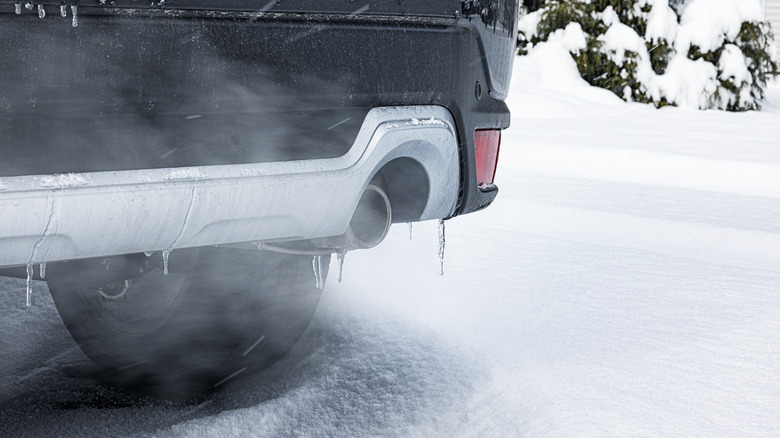 Close-up of car exhaust running in snowy driveway