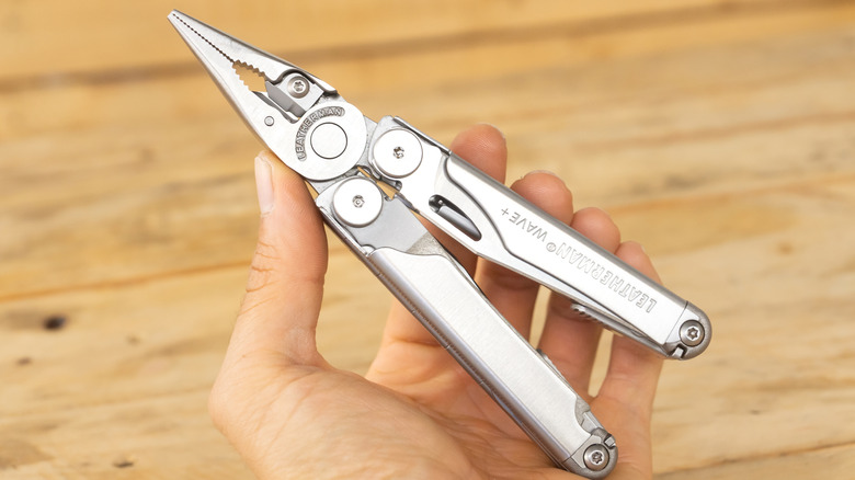 Silver multi-tool with pliers out sitting on a couch