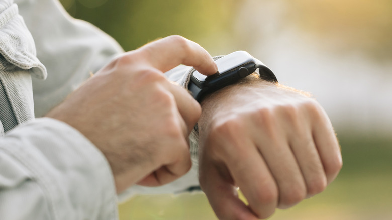 Close up shot of male's hand uses of wearable smart watch at outdoor in sunset..
