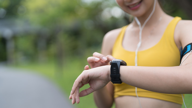 Young woman tracking pace, speed and heart rate with fitness tracker app on smartwatch.