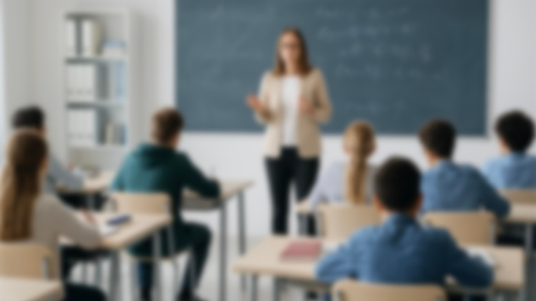 Blurred image of a female teacher in front of a classroom of students