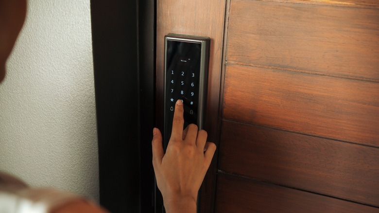 A person tapping their finger on a numeric keypad on a door