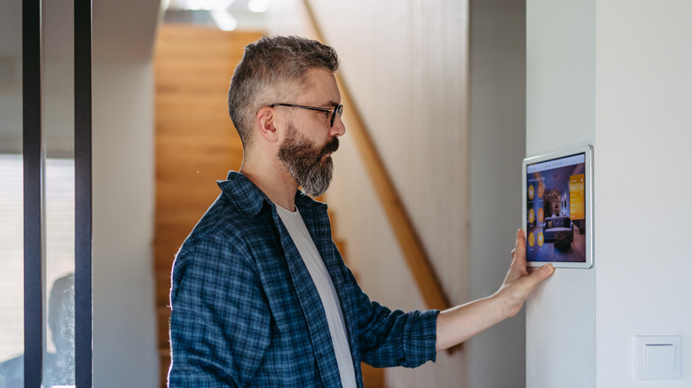 Man touching a screen on a wall in a home