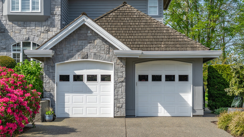 A home viewed from outside, stone walls and two white garage doors visible