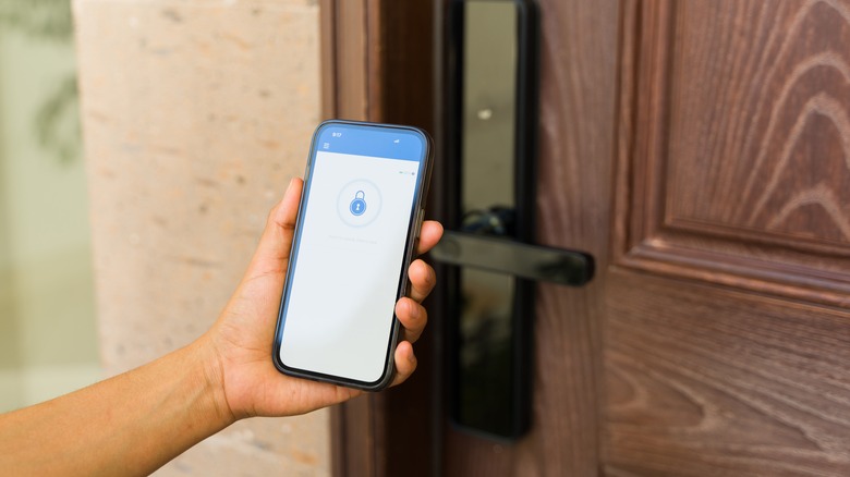 A hand holding a smartphone next to a door