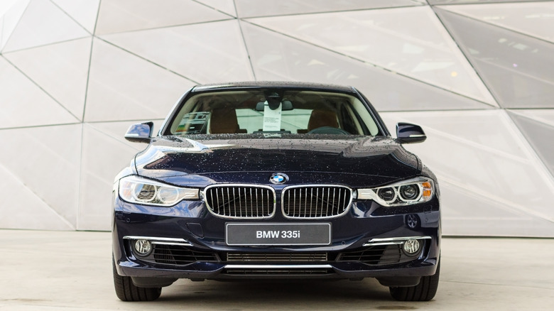 A black BMW 335i exhibited indoors at an event, front fascia prominently visible