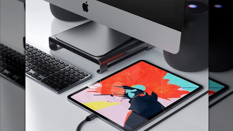 Clean desk showing an Apple computer, keyboard, and charging iPad