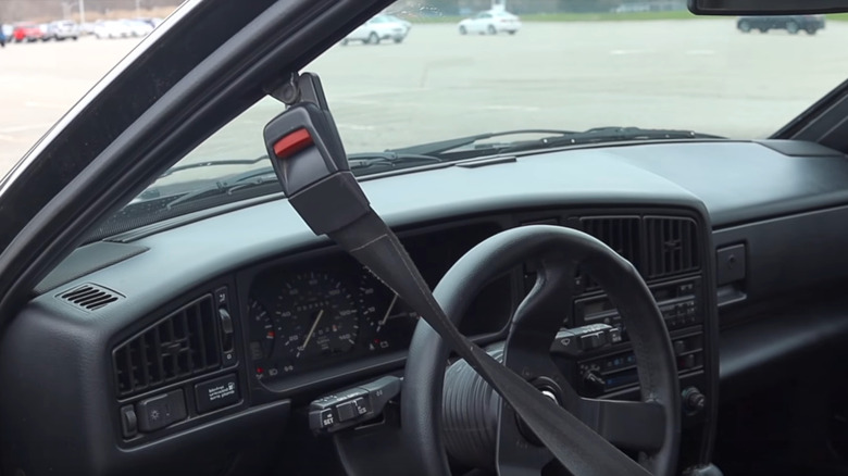 Interior of a 1988 Volkswagen Corrado showing the driver's side with a motorized automatic shoulder seatbelt on the door frame.