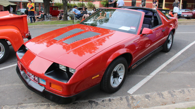 A bright red third-generation Chevrolet Camaro Z28 with T-top roof panels.