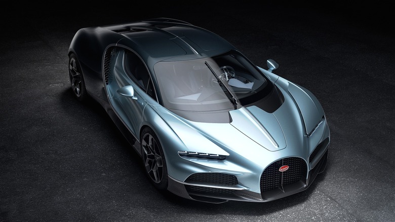 A sleek silver 2026 Bugatti Tourbillon hypercar sitting dramatically in a tunnel-like studio.