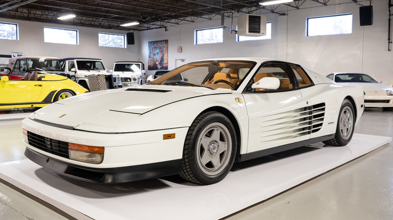 A white Ferrari Testarossa sitting on a display stand in a museum
