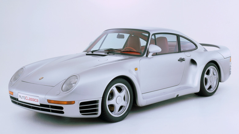 A silver Porsche 959 with a red interior on display at a museum