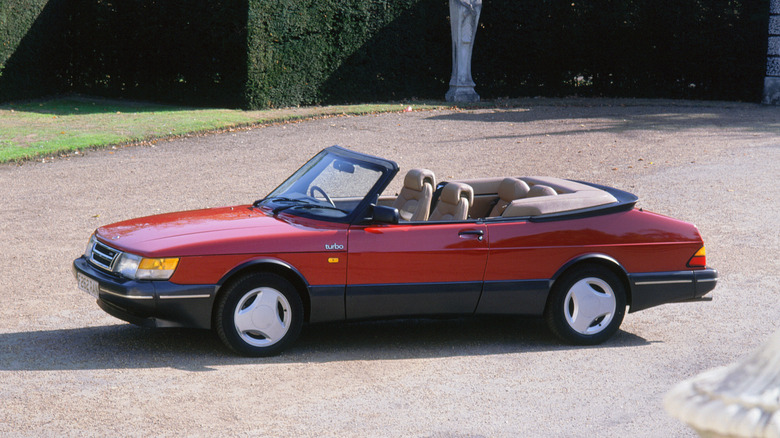 Red 1989 Saab 900 Turbo Convertible parked in the dirt driveway of a mansion
