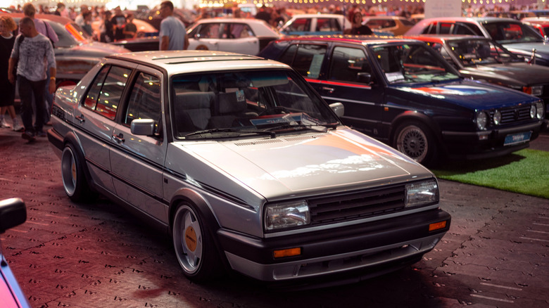 A silver Volkswagen Jetta Mk2 sedan displayed indoors at a classic car show.