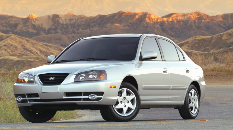 A silver Hyundai Elantra sedan parked on a road with mountains in the background.
