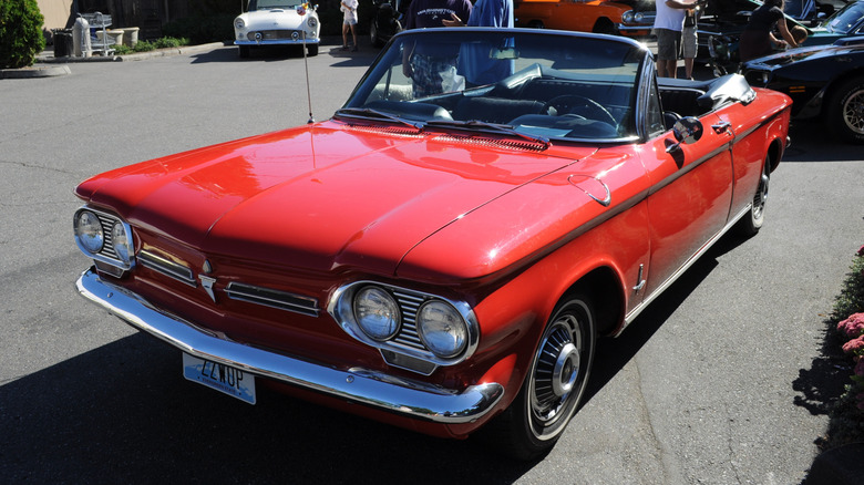 Red 1962 Chevrolet Corvair Monza convertible seen from front left parked at an outdoor car show