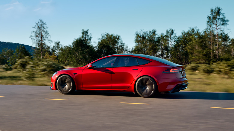 Red Tesla Model S seen from left driving on a mountain road