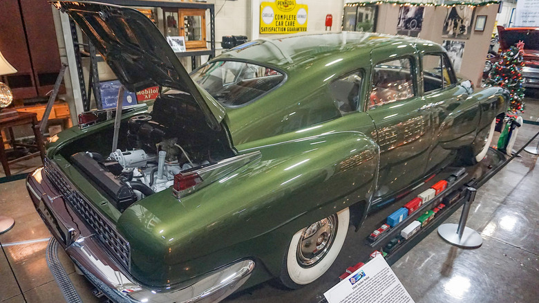 Green 1948 Tucker 48 "Torpedo" sedan on display at Stahls Automotive Collection with trunk open to display rear engine
